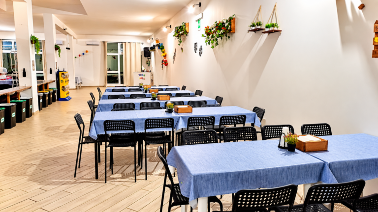 Sala eventi luminosa con tavoli blu e piante decorative